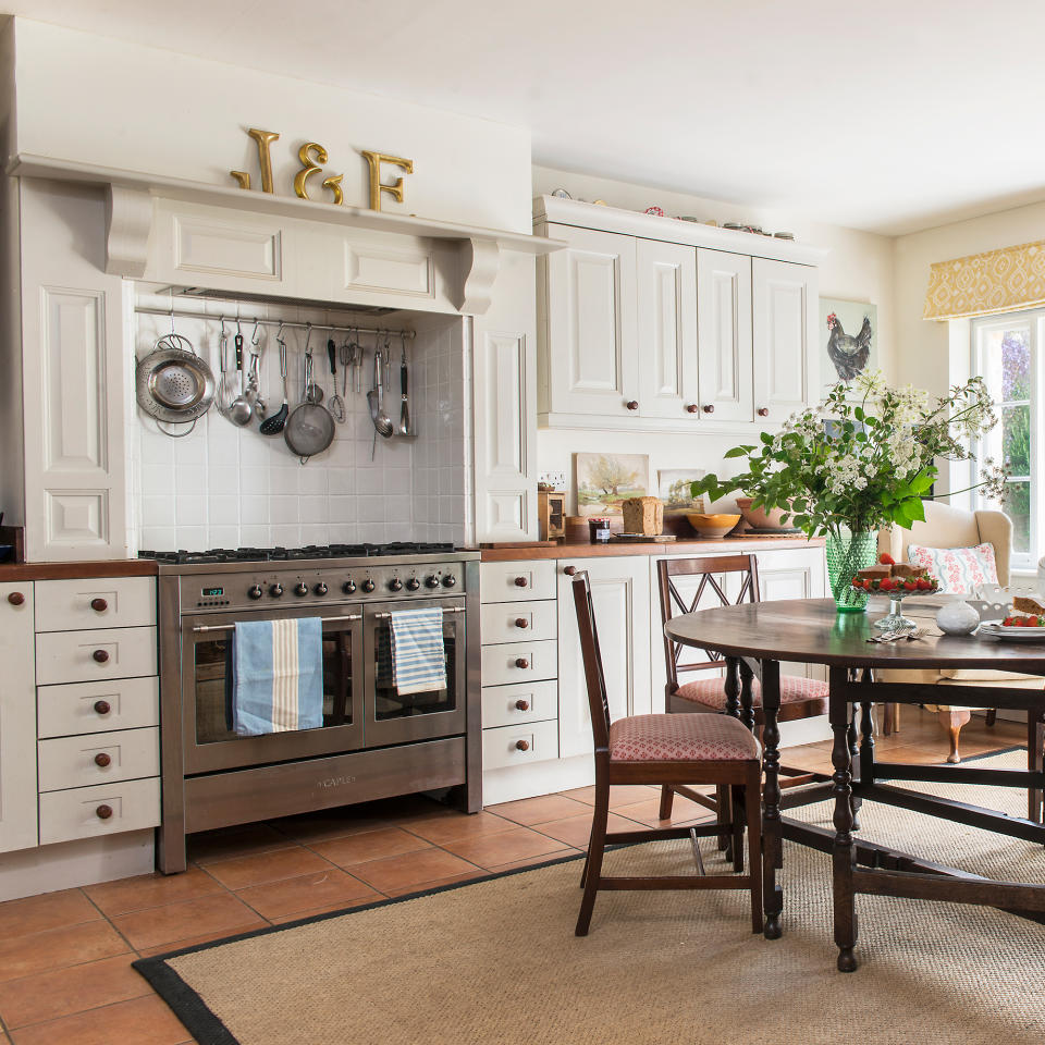 Cream painted traditional kitchen units and silver range cooker in a fireplace recess