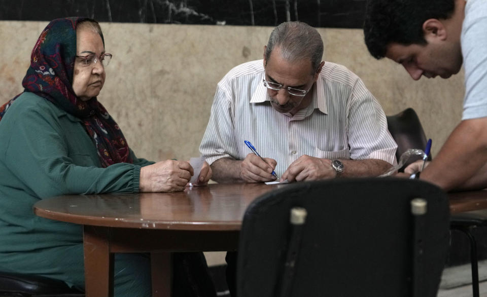 Voters fill out their ballots for the presidential runoff election at a polling station in Tehran, Iran, Friday, July 5, 2024. Iranians are voting in a runoff election to replace the late President Ebrahim Raisi, who was killed in a May helicopter crash in the country’s northwest along with the foreign minister and several other officials. (AP Photo/Vahid Salemi)