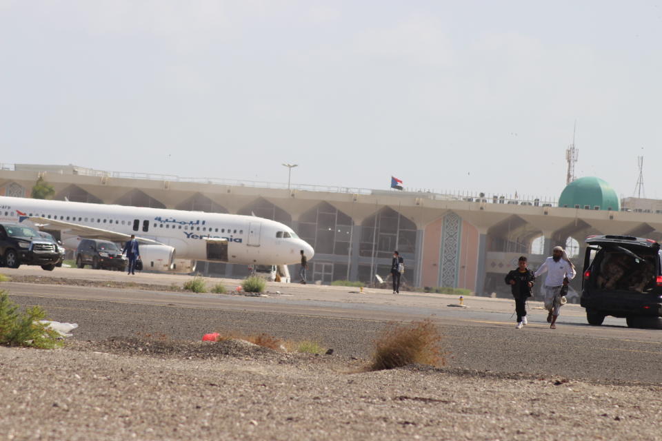 People walk away from the runway following an explosion at the airport in Aden, Yemen, shortly after a plane carrying the newly formed Cabinet landed on Wednesday, Dec. 30, 2020. No one on board the government plane was hurt but initial reports said several people at the airport were killed. (AP Photo/ Wael Qubady)