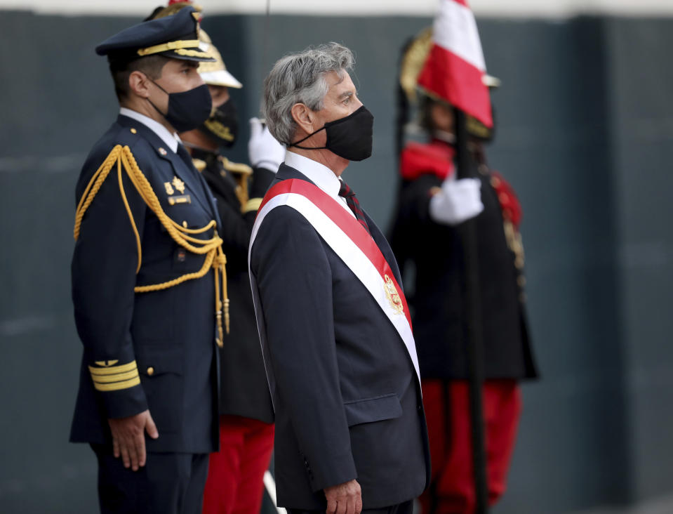 Francisco Sagasti, center, stands at attention during the national anthem, after being sworn-in as the new, interim president at Congress in Lima, Peru, Tuesday, Nov. 17, 2020. Sagasti's appointment marks a tumultuous week in which thousands took to the streets outraged by Congress' decision to oust popular ex-President Martín Vizcarra. (AP Photo/Rodrigo Abd)