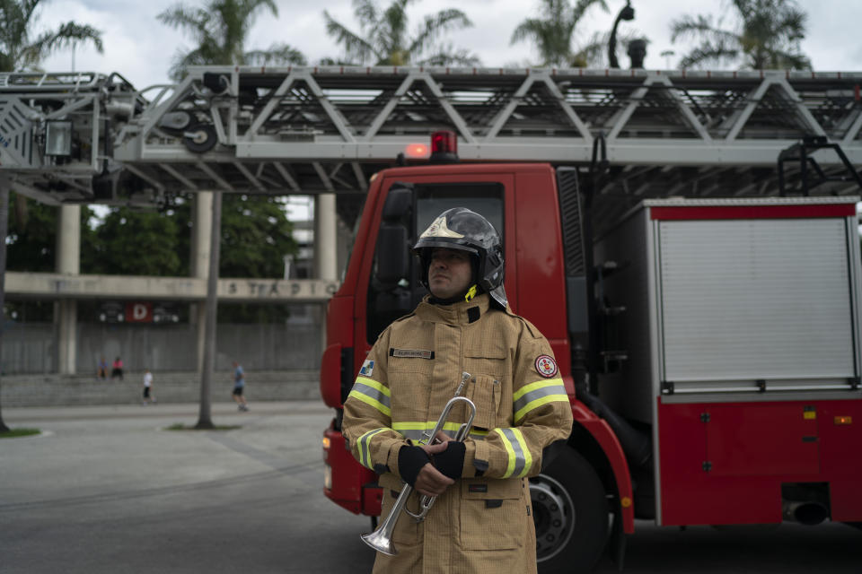 El bombero Elielson Silva se prepara para iniciar un recorrido en el que tocará su trompeta desde lo alto de la escalera de su camión para entretener a los cariocas en medio del encierro del coronavirus el 5 de abril del 2020 en Río de Janeiro. Toca con uniforme y casco a pesar del fuerte calor. (AP Photo/Leo Correa)