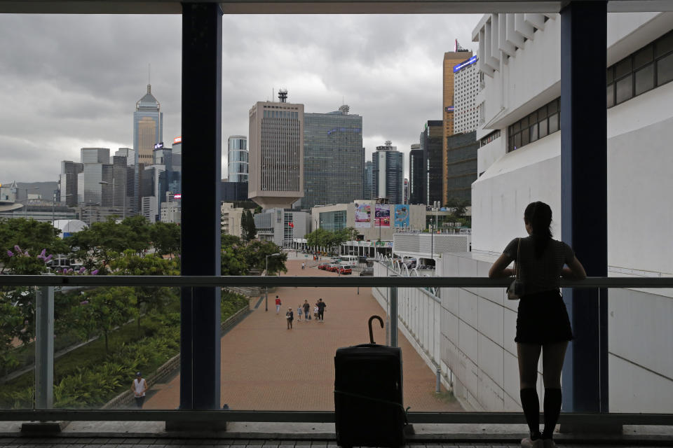 In this June 10, 2019, photo, a woman stands near the skyline of Hong Kong at Central, business district of Hong Kong. It’s still the world’s “freest” economy, one of the biggest global financial centers and a scenic haven for tycoons and tourists, but the waves of protests rocking Hong Kong are exposing strains unlikely to dissipate as communist-ruled Beijing’s influence grows.(AP Photo/Kin Cheung)