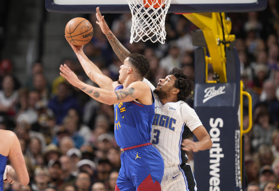 Denver Nuggets forward Michael Porter Jr., left, drives to the basket as Orlando Magic forward Chuma Okeke, right, defends in the first half of an NBA basketball game Friday, Jan. 5, 2024, in Denver. (AP Photo/David Zalubowski)