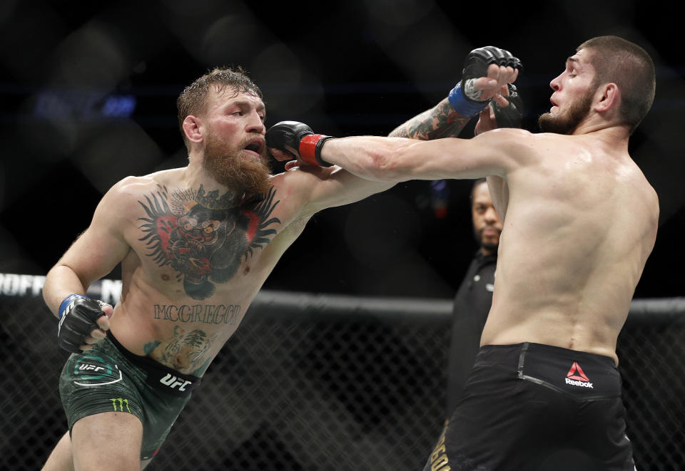 Conor McGregor, left, and Khabib Nurmagomedov throw punches during a lightweight title mixed martial arts bout at UFC 229 in Las Vegas, Saturday, Oct. 6, 2018. (AP Photo/John Locher)