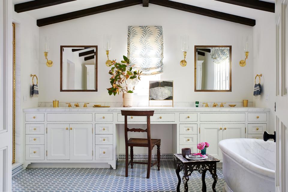 The main bath’s Carrara marble tub from Urban Archaeology was so massive it had to be craned into the window. A roman shade made in Soane fabric and Ann-Morris sconces help keep the vibe light and airy, while an inlaid chair and table from JF Chen impart a sense of age.