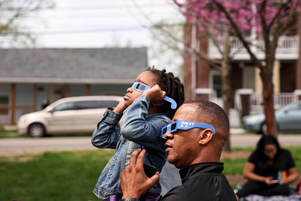 Dr. Lezell Lowe holds his granddaughter, Niyeah, as people gather to view a total solar eclipse seen from the Living Arts & Science Center in Lexington, Ky., Monday, April 8, 2024. Silas Walker/swalker@herald-leader.com