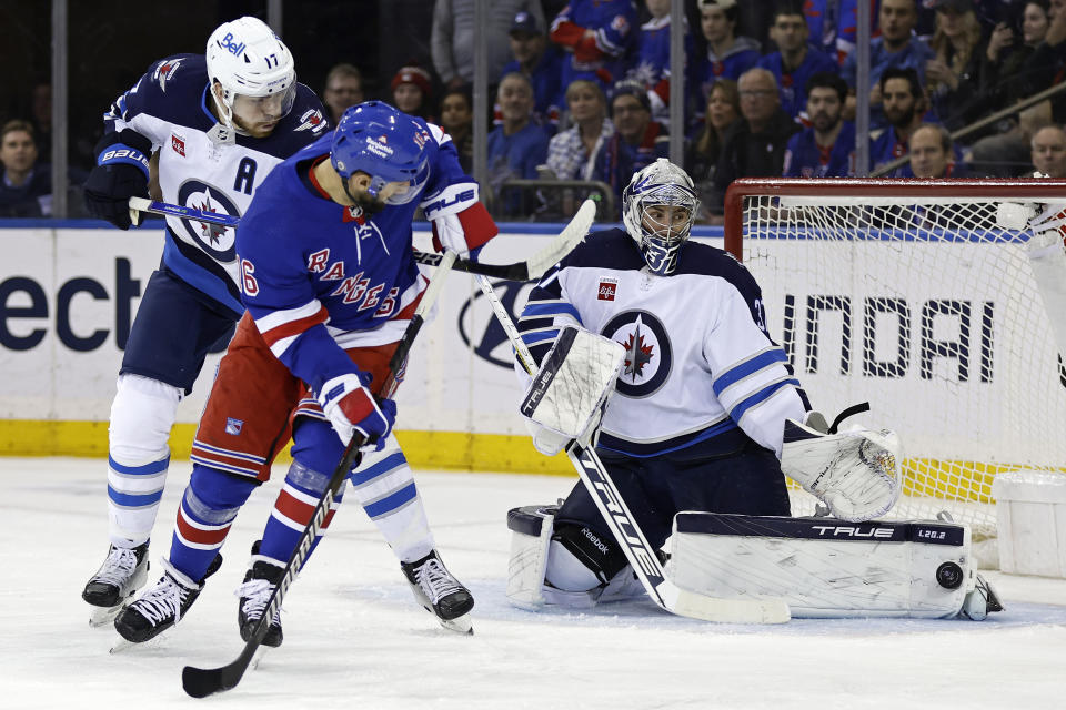 Winnipeg Jets goaltender Connor Hellebuyck, right, makes a save in front of New York Rangers center Vincent Trocheck, front left, in the first period of an NHL hockey game Monday, Feb. 20, 2023, in New York. (AP Photo/Adam Hunger)