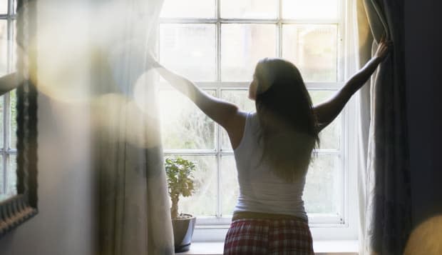 woman opening curtains in the morning