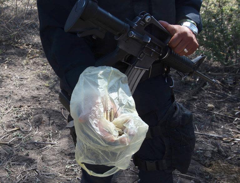 A state policeman shows empty rifle cartridges found during a search for evidence inside the ranch along the Jalisco-Michoacan highway in Tanhuato, Michoacan State on May 23, 2015