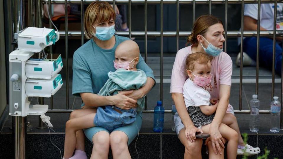 Children with IV drips sitting outside a Kyiv hospital