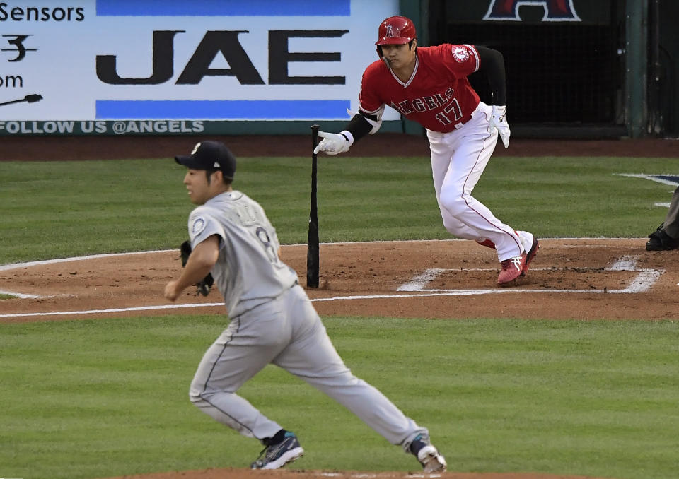 Los Angeles Angels' Shohei Ohtani, right, runs to first for a single as Seattle Mariners starting pitcher Yusei Kikuchi runs to back up the first baseman during the first inning of a baseball game Saturday, June 8, 2019, in Anaheim, Calif. (AP Photo/Mark J. Terrill)