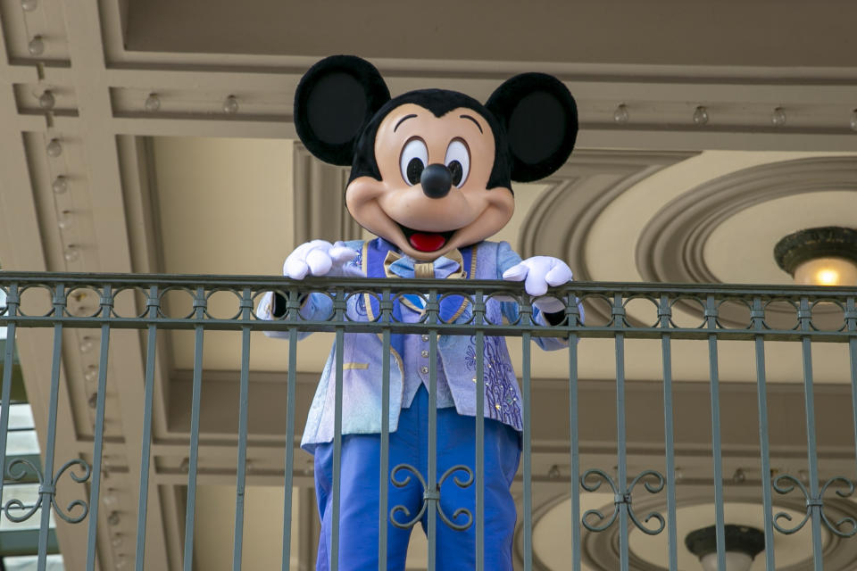 ARCHIVO - Un actor vestido como Mickey Mouse saluda a visitantes en la entrada del Parque Temático Magic Kingdom en Walt Disney World Resort, el 18 de abril de 2022, en Lake Buena Vista, Florida. Winnie the Pooh y Mickey Mouse han entrado recientemente en el dominio público, lo que hace posible que los artistas los usen libremente. (Foto AP/Ted Shaffrey, archivo)