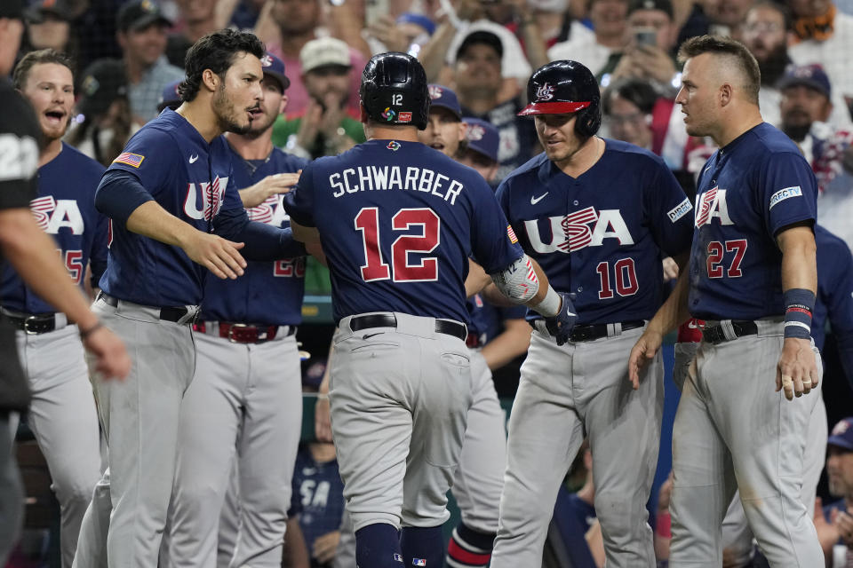 The U.S. team congratulates Kyle Schwarber (12) after hitting a home run during the eighth inning of a World Baseball Classic final game against Japan, Tuesday, March 21, 2023, in Miami. Japan defeated the U.S. 3-2. (AP Photo/Marta Lavandier)