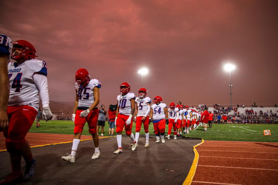 Indio players head to the locker room as the game is suspended after nearby lightning strikes were seen during the first quarter of their game at Shadow Hills High School in Indio, Calif., Friday, Aug. 18, 2023. 