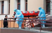 Medical employees wearing protective suits move a capsule with a woman inside in Minsk