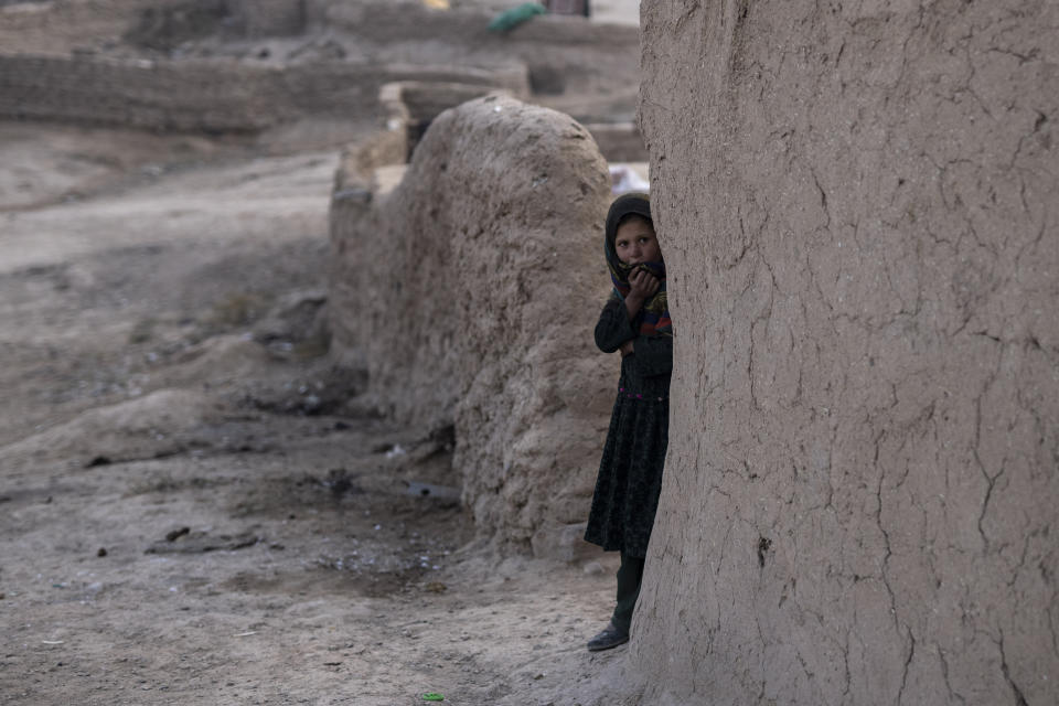 FILE - An Afghan girl looks out of her house in Kamar Kalagh village near Herat, Afghanistan, on Nov. 27, 2021. The United Nations is predicting that a record 274 million people – who together would amount to the world’s fourth most-populous country – will require emergency humanitarian aid next year in countries including Afghanistan, Ethiopia, Myanmar, Syria and Yemen as they face a raft of challenges such as war, insecurity, hunger, climate change and the coronavirus pandemic. (AP Photo/Petros Giannakouris, File)