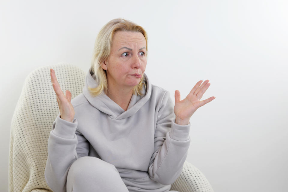 An upset woman wearing a hoodie and sitting in a chair