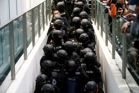 Armed policemen take the escalator as they escort Indonesian Siti Aisyah and Vietnamese Doan Thi Huong, who are on trial for the killing of Kim Jong Nam, the estranged half-brother of North Korea's leader, at the Kuala Lumpur International Airport 2 in Sepang, Malaysia October 24, 2017. REUTERS/Lai Seng Sin