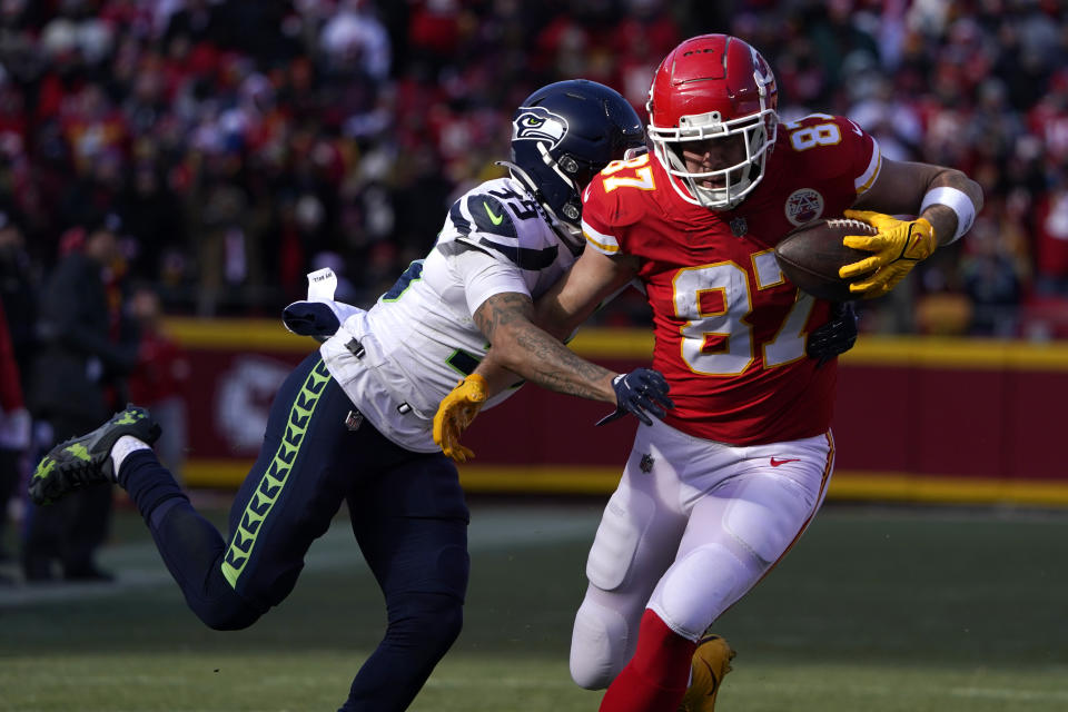 Kansas City Chiefs tight end Travis Kelce (87) catches a pass as Seattle Seahawks safety Teez Tabor (39) defends during the first half of an NFL football game Saturday, Dec. 24, 2022, in Kansas City, Mo. (AP Photo/Ed Zurga)