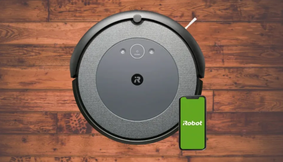 A grey and black robot vacuum with a smartphone screen reading 