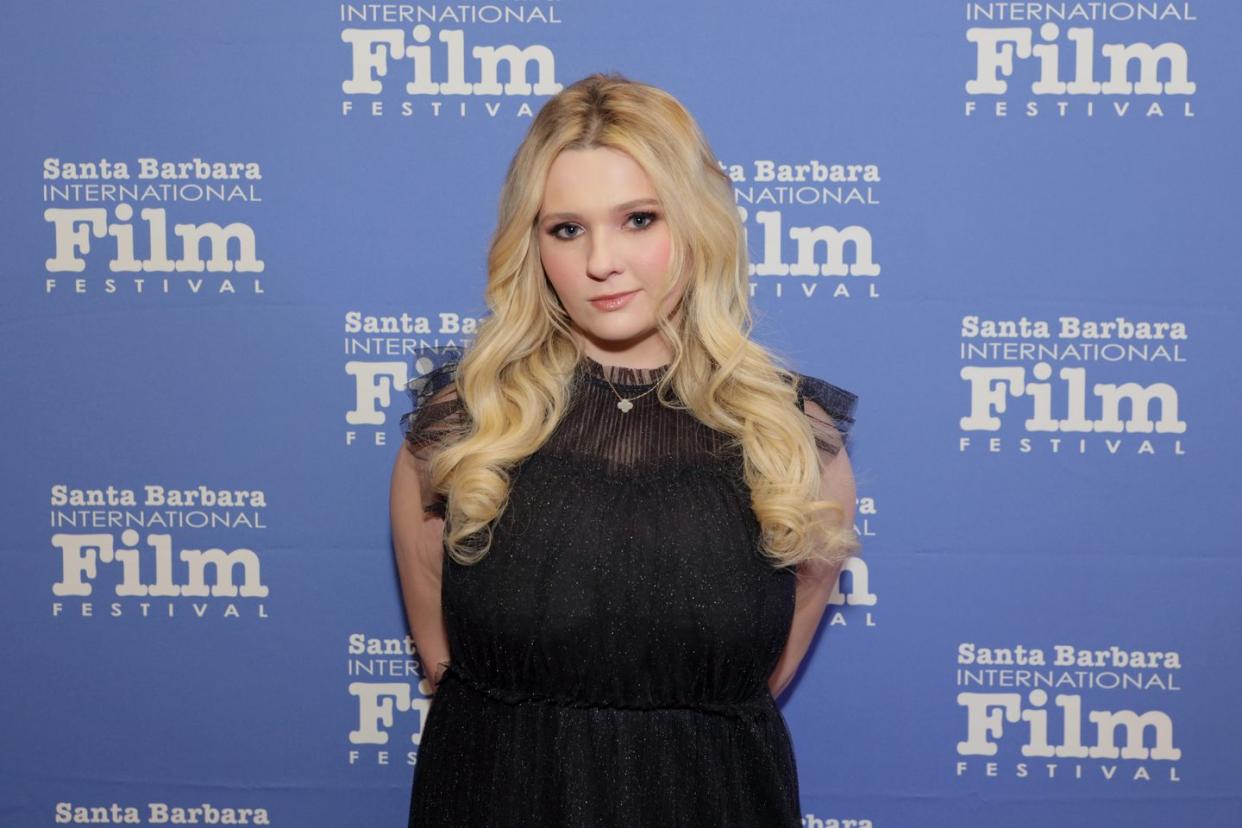 abigail breslin with her blonde hair in curls and wearing a black dress