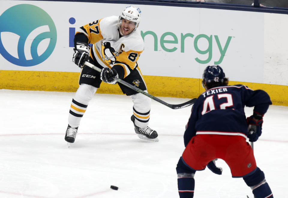 Pittsburgh Penguins forward Sidney Crosby, left, passes the puck in front of Columbus Blue Jackets forward Alexandre Texier during the third period of an NHL hockey game in Columbus, Ohio, Friday, Jan. 21, 2022. The Penguins won 5-2. (AP Photo/Paul Vernon)