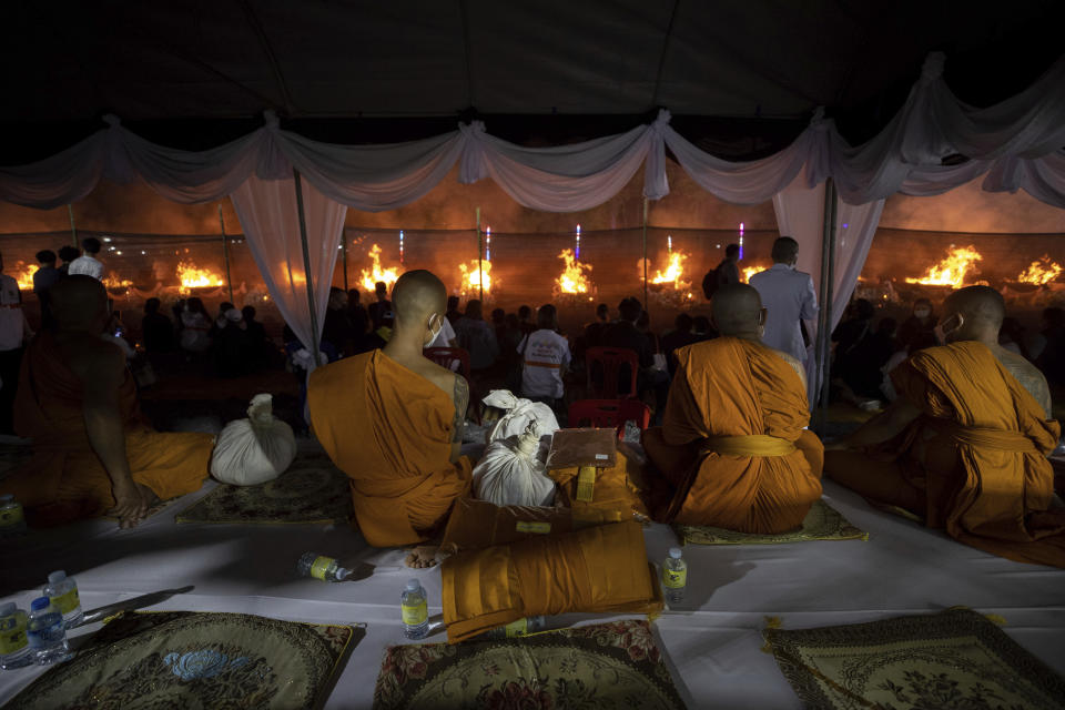 Monks sit and watch at funeral pyres set to cremate those who died in the day care center attack at Wat Rat Samakee temple in Uthai Sawan, northeastern Thailand, Tuesday, Oct. 11, 2022. A former police officer burst into a day care center in northeastern Thailand on Thursday, killing dozens of preschoolers and teachers before shooting more people as he fled. (AP Photo/Wason Wanichakorn)