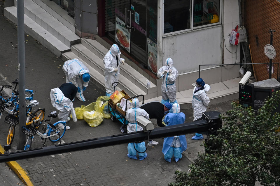 Workers take off protective gear next to the entrance of a locked-down neighborhood during a pandemic lockdown in Jing'an district in Shanghai, China, April 5, 2022. / Credit: HECTOR RETAMAL/AFP/Getty