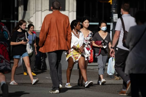 Pedestrians, some wearing facemasks and some not, cross a busy intersection in Vancouver on Tuesday, Aug.10, 2021.  (Maggie MacPherson/CBC - image credit)