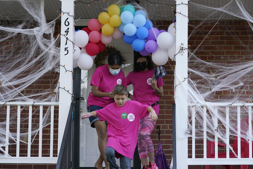 In this Saturday, Oct. 16, 2021, photo Han Jones, left, and Lucy Hartman, right, of Planned Parenthood Advocates of Virginia, along with Henry Pickett, center, leave a porch decorated for Halloween as they canvass the area to encourage voters to vote in Richmond, Va. (AP Photo/Steve Helber)