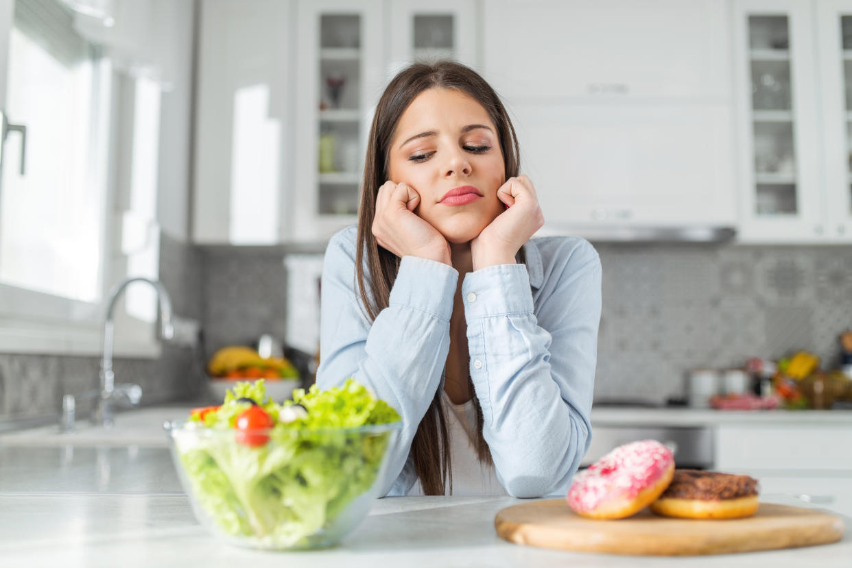 girl chooses between donuts and vegetable salad