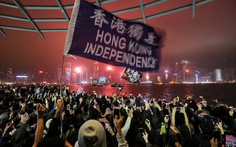 Protesters chant as fireworks explode in Hong Kong along the waterfront on new year's eve in Tsim Sha Tsui  - Credit: Rex