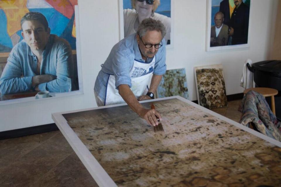 Raymond Elman in his Miami studio with his portraits in the background.