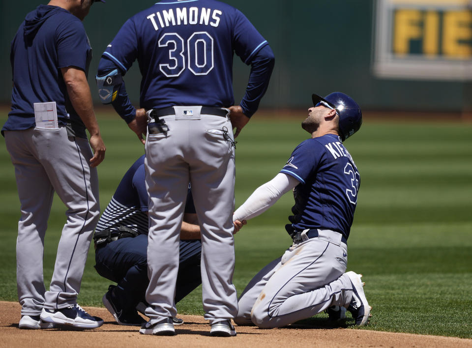 Tampa Bay Rays' Kevin Kiermaier, right, is looked at by a trainer after stealing second base during the second inning of a baseball game against the Oakland Athletics, Saturday, May 8, 2021, in Oakland, Calif. (AP Photo/Tony Avelar)