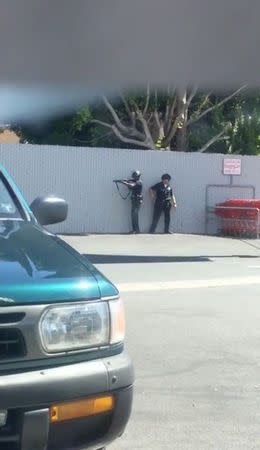 Police officers take position after a suspected gunman being pursued by police crashed his car and then went into a Trader Joe's store in Los Angeles, California, the U.S., July 21, 2018, in this still image taken from a video obtained from social media. @Lorisqueen/via REUTERS