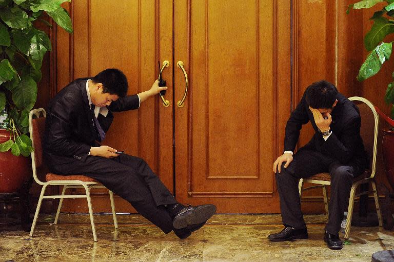 Two security officers sit at the entrance of a hotel lounge where relatives of passengers from the missing Malaysia Airlines flight MH370 are gathered in Beijing on March 19, 2014