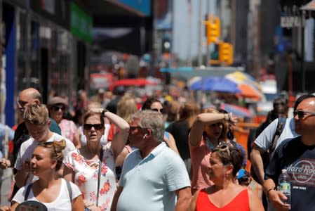 People react while walking through Times Square as a heatwave continues to affect the region in New York