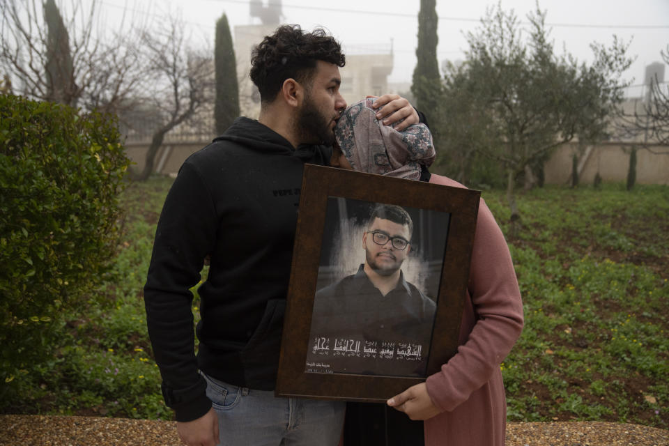 Amir Abdel Jabbar, cuyo hermano menor Tawfic fue muerto a tiros la semana pasada, consuela a su madre, Mona, quien sostiene una foto enmarcada de la familia en su aldea de Al-Mazra'a ash-Sharqiya, Cisjordania, 23 de enero de 2024. Tawfik era estadounidense, de Luisiana, y la Casa Blanca ha exigido una investigación transparente de su muerte. (AP Foto/Nasser Nasser)