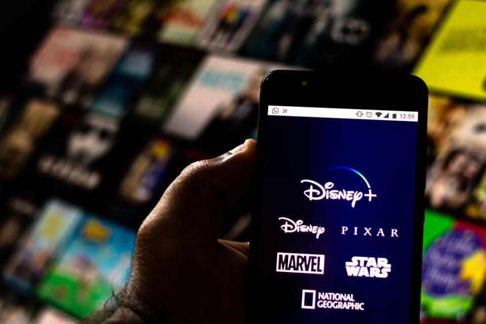 Pictured: Phone with Disney Plus logo and information, backdrop of Disney+ films. Image: Getty