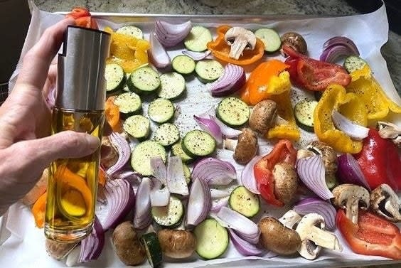 A reviewer spraying vegetables with the oil spray