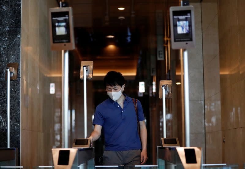 A man wearing a protective face mask demonstrates the facial recognition and elevator navigation systems, at the entrance hall of SoftBank's new headquarters building in Tokyo