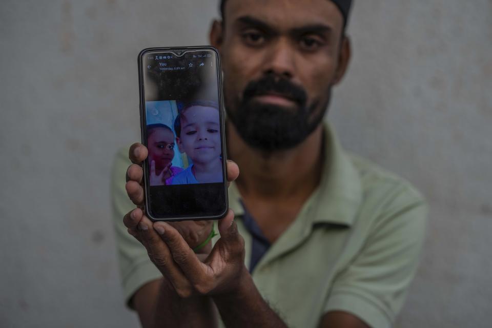 Arif Shamdar shows a photograph of his children Afreed 6, and Aliya, 8, on a phone in Morbi town of western state Gujarat, India, Tuesday, Nov. 1, 2022. “Everyone I loved is dead,” said Shamdar, whose wife Aneesa and two children died in a bridge that collapsed on Sunday. Friends have lost friends. Parents have lost children who were on the bridge to sightsee and enjoy the weekend after holiday festivities. And in many cases, half the families have been wiped out. (AP Photo/Rafiq Maqbool)