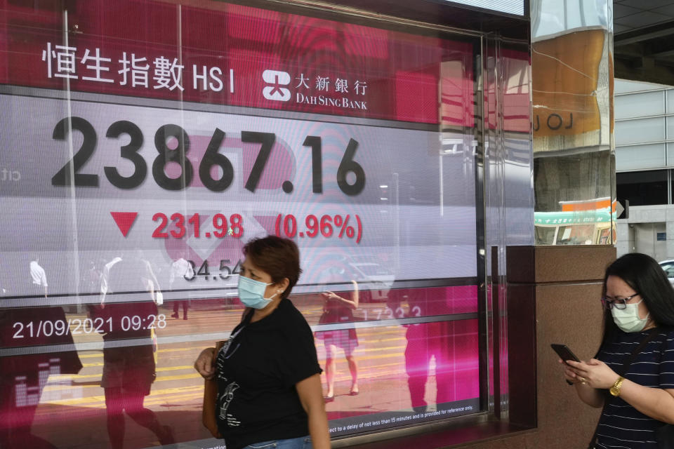 A woman walks past a bank's electronic board showing the Hong Kong share index at Hong Kong Stock Exchange in Hong Kong Tuesday, Sept. 21, 2021. Asian shares declined Tuesday, with Tokyo down 2% as worries about heavily indebted Chinese real estate developers weighed on sentiment. (AP Photo/Vincent Yu)