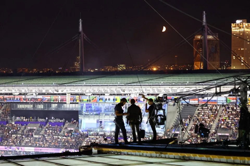 Tom Cruise with aides on the roof of the Stade de France during the closing ceremony.