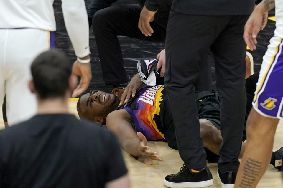 An injured Phoenix Suns guard Chris Paul grimaces in pain during the first half of Game 1 of their NBA basketball first-round playoff series against the Los Angeles Lakers Sunday, May 23, 2021, in Phoenix. (AP Photo/Ross D. Franklin)