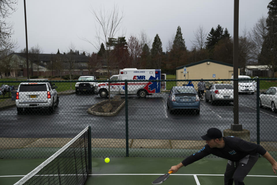 Myles Baida plays pickleball after emergency responders put a homeless person in an ambulance on Saturday, March 23, 2024, in Grants Pass, Ore. Relatives had called police and requested a welfare check. (AP Photo/Jenny Kane)