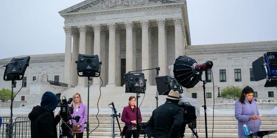 Television news crews stand at the Supreme Court, May 3, 2022, in Washington