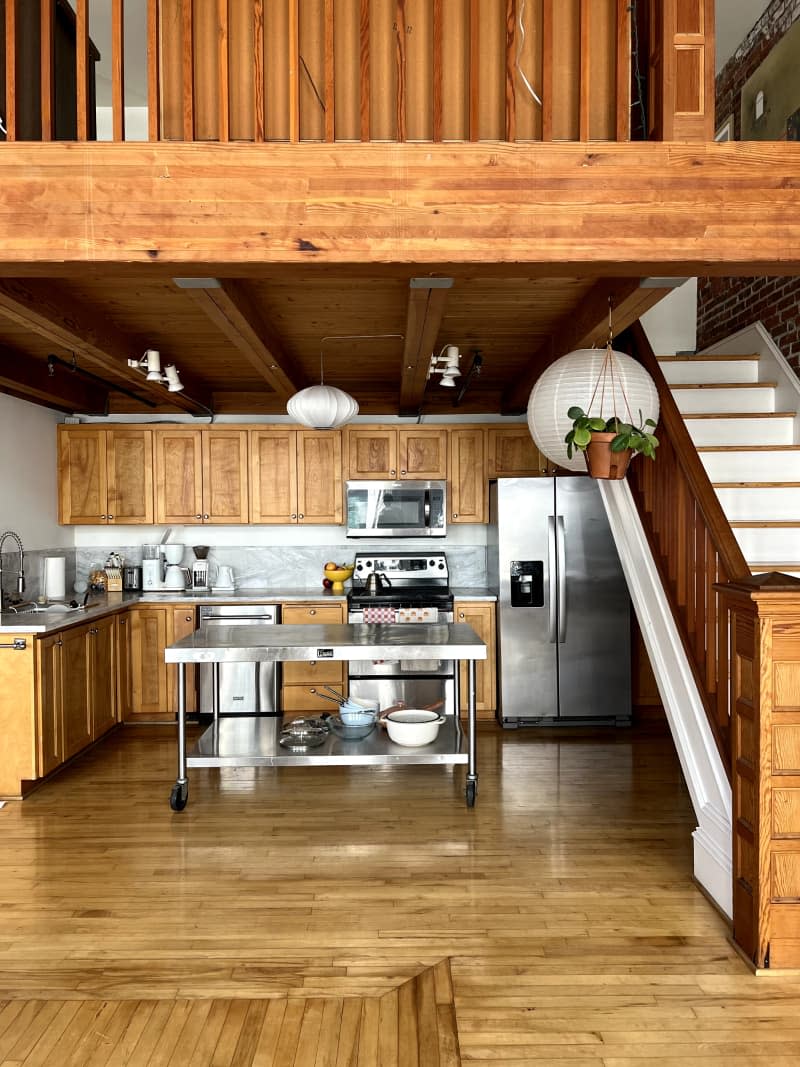 Kitchen with wood cabinets and stainless steel appliances located under loft space.