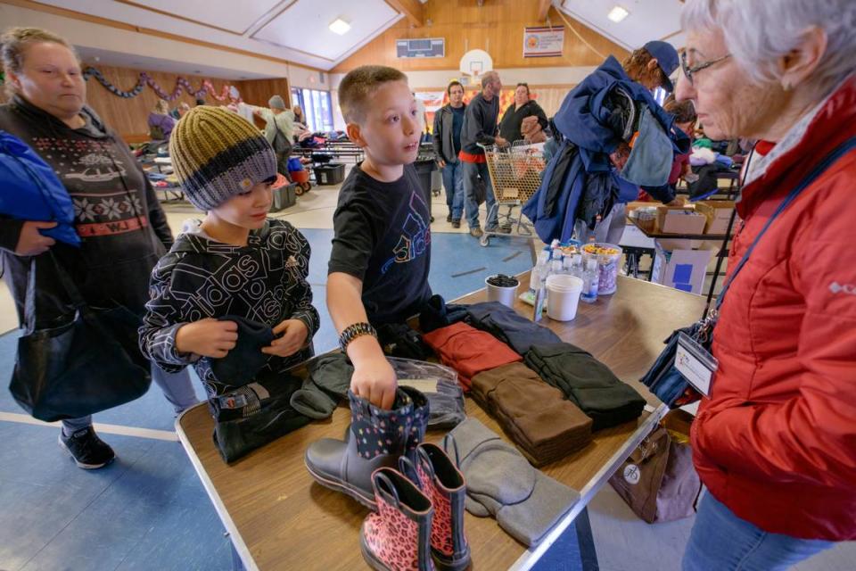 Christopher Randall 9, left, and Julian Beaudion select from donated gloves and hats at Pioneer Elementary School in Pioneer on Sunday, Dec. 18. The event was hosted by the West Slope Association, to provide free clothing and personal items to Grizzly Flats residents who lost their homes in the Caldor Fire.