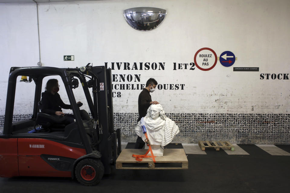 Workers transport a bust of Guillaume de Lamoignon by French sculptor Francois Girardon, in the Louvre museum, in Paris, Wednesday, Feb. 17, 2021. The forced closure has granted museum officials a golden opportunity to carry out long-overdue refurbishments that were simply not possible with nearly 10 million visitors a year. (AP Photo/Thibault Camus)